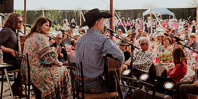 Songwriter Shuffle Concert under a tent with performers singing to a large crowd.