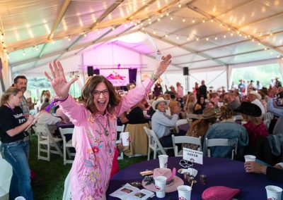 A happy winning bidder jumps up with a great big smile, arms held high.