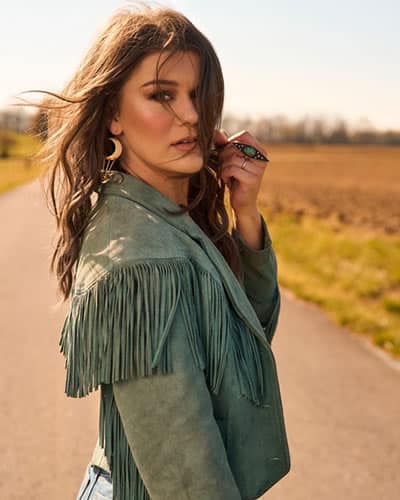Mae Estes Mae Estes standing on a country road wearing a green leather jacket and beautiful jewelry.